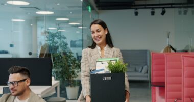 Woman carrying box of belongings leaving office